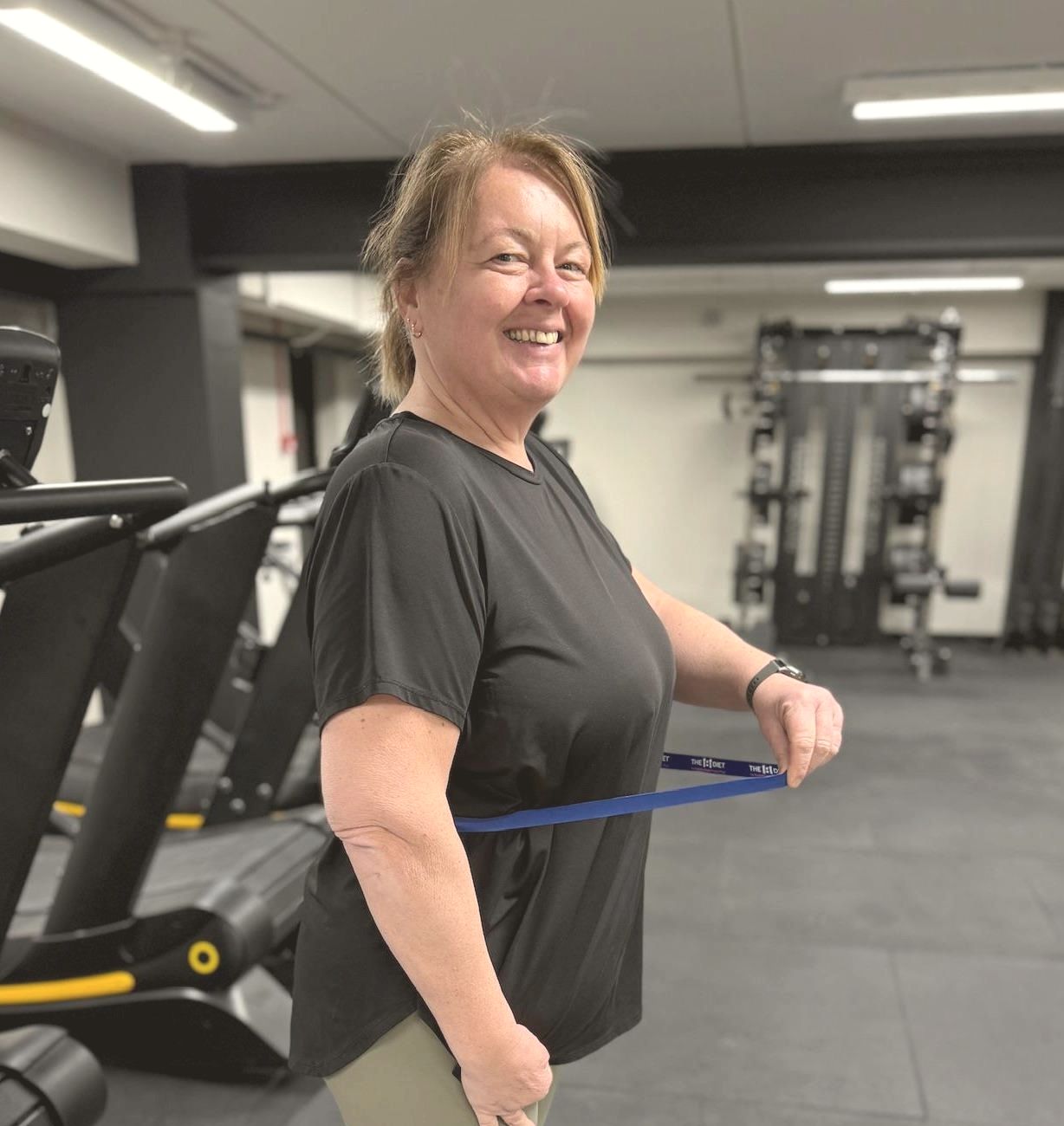 A smiling member warming up with a resistance band in the studio